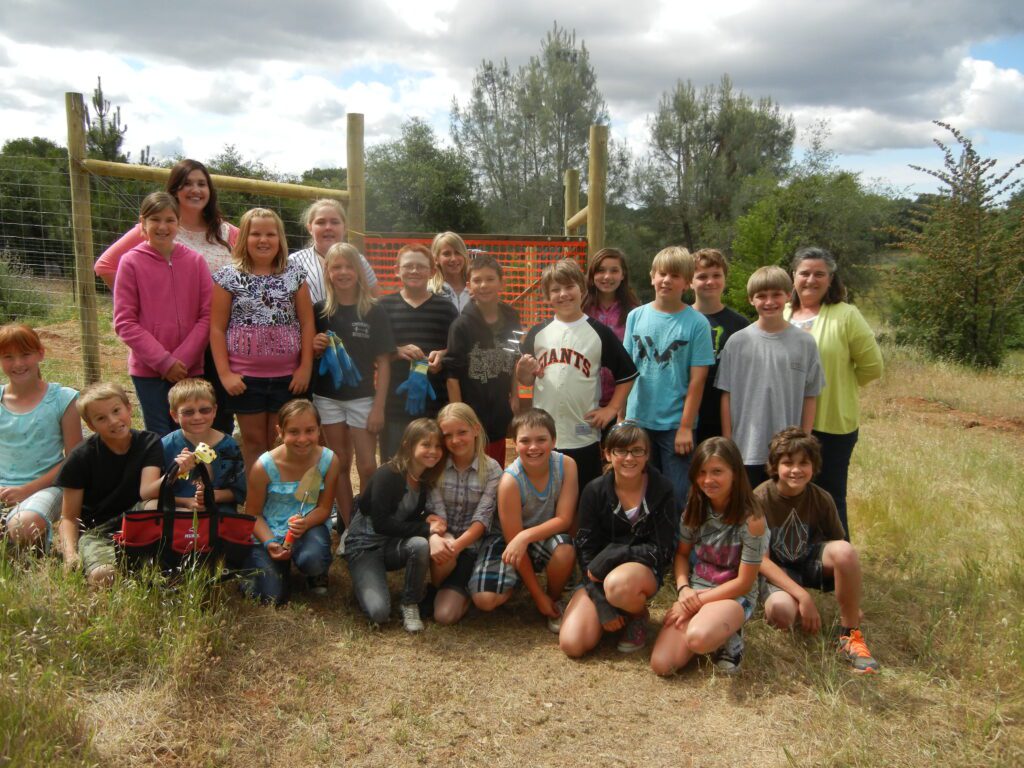 a group photo of adults and children together outside