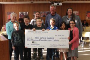 Children holding a large check with adults standing behind